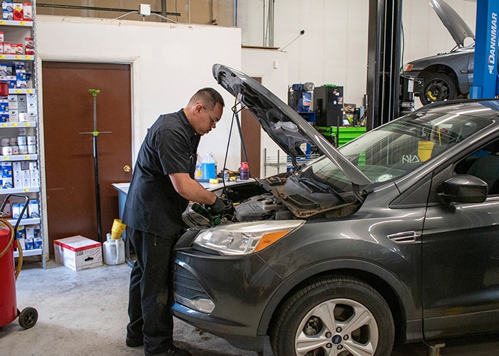 A technician performing maintenance on a car's air conditioning system