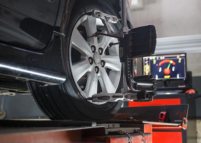 Car alignment equipment in use, with sensors and tools aligning the vehicle's wheels.