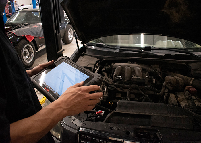 a person using a tablet to diagnose the engine of a car