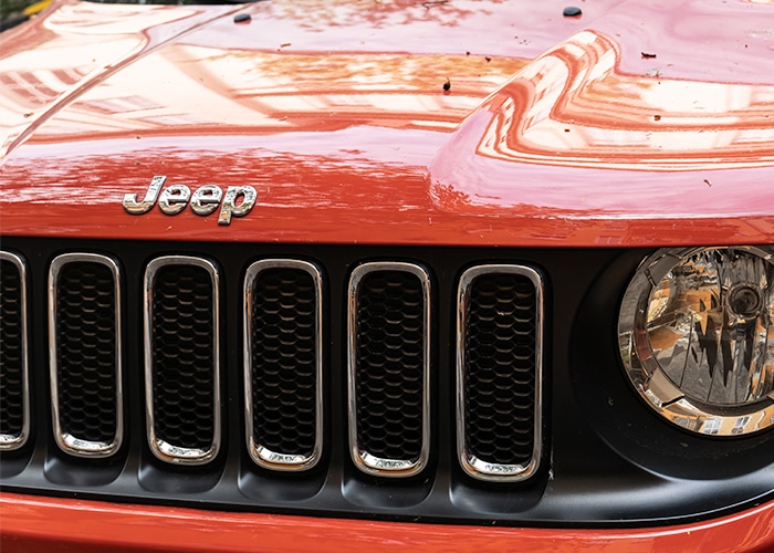 The front view of an orange Jeep vehicle, showcasing its distinctive grille and headlights.