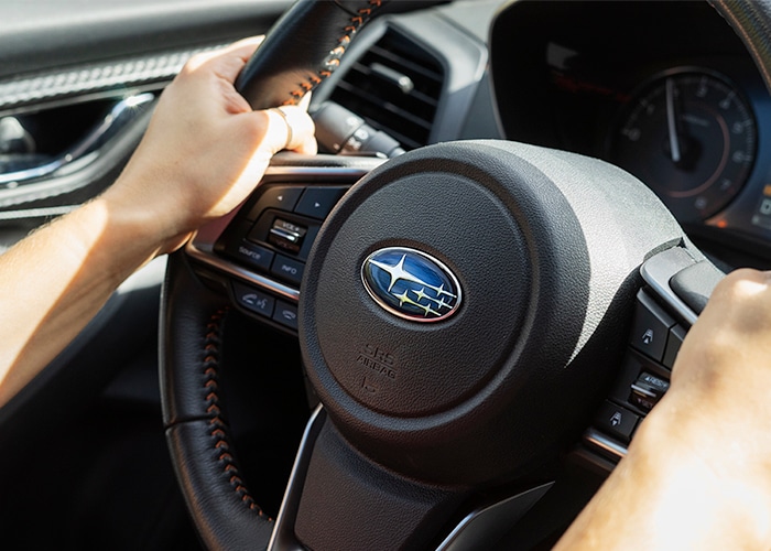 a hand on a Subaru steering wheel
