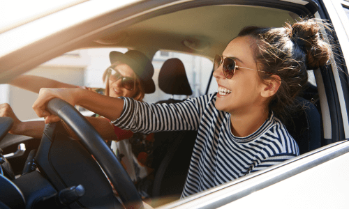 image of two women in sunglasses driving happily in car