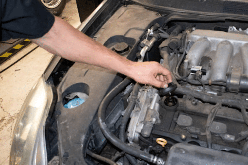 seasonal car care in Northglenn, CO with Accurate Automotive. Image of mechanic hand opening oil cap on the engine in the shop while performing preventative maintenance.