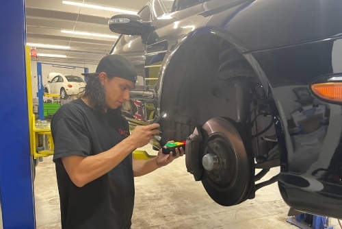 Brake repair services near me in Northglenn, CO at Accurate Automotive. Technician performing brake repair on a lifted car.