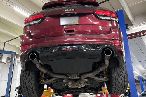 Exhaust repair in Northglenn, CO by Accurate Automotive. Image of a Jeep Grand Cherokee SRT lifted in a shop for service, highlighting the shop’s dedication to performance, precision, and keeping vehicles safe on the road.